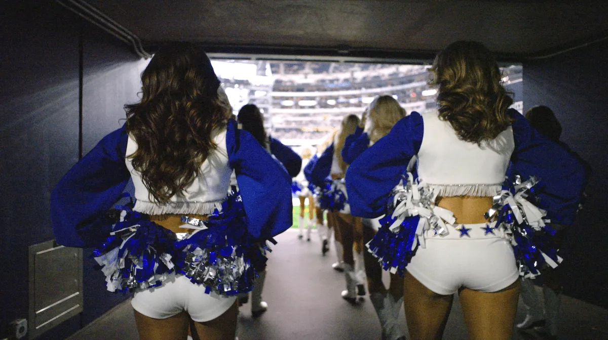 Dallas Cowboys Cheerleaders, shown from behind, walking onto the field