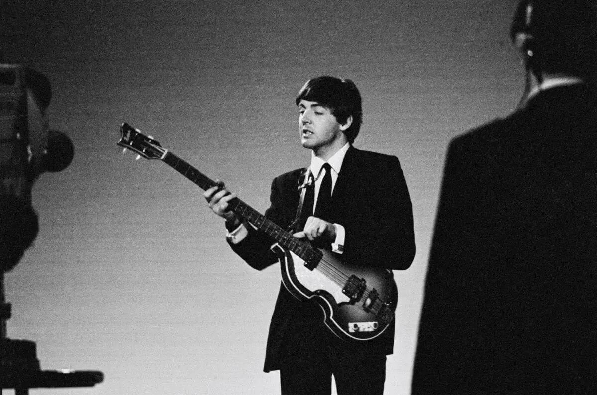 A black and white picture of The Beatles' Paul McCartney holding a bass guitar.