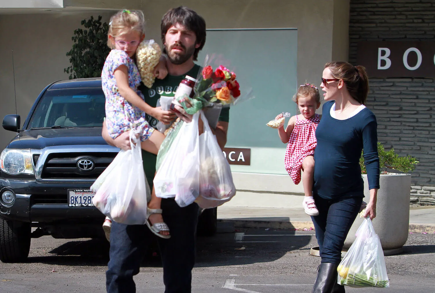 Ben Affleck carrying one of his kids and groceries from the Brentwood Farmers Market while Jennifer Garner walks behind him carrying another child on Oct. 16, 2011