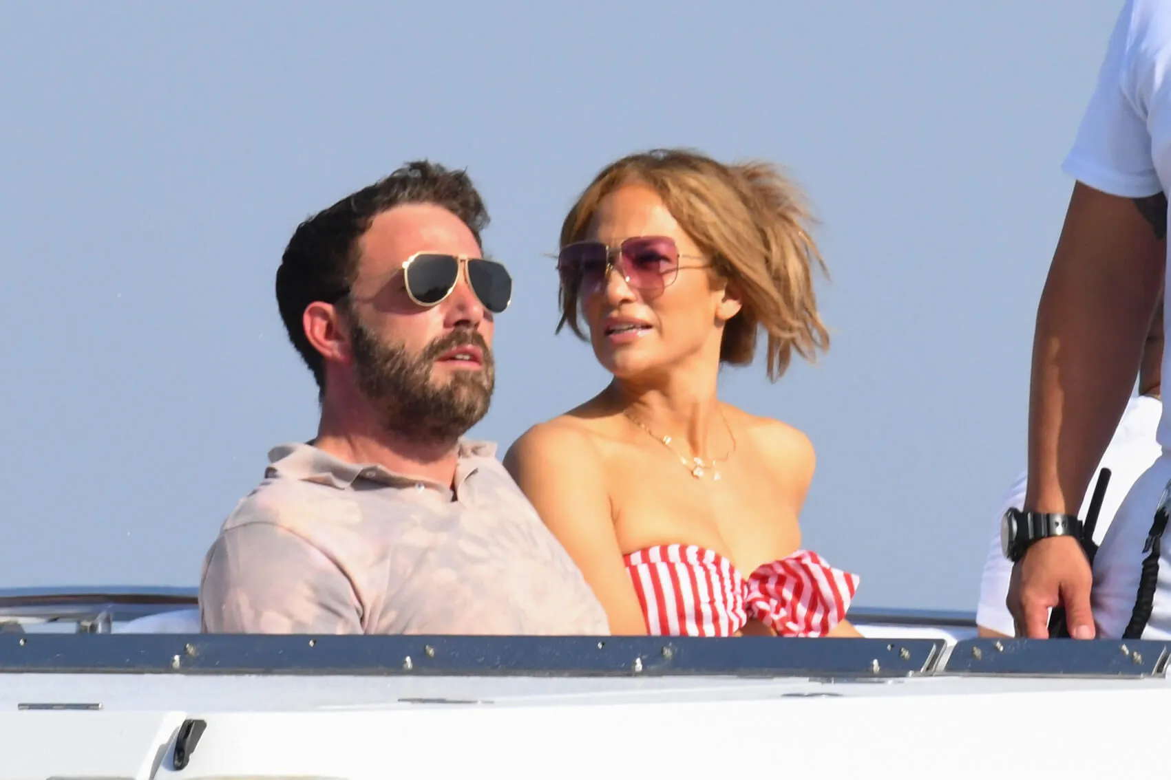 Ben Affleck and Jennifer Lopez sitting next to each other and wearing sunglasses on a boat in Italy in 2021