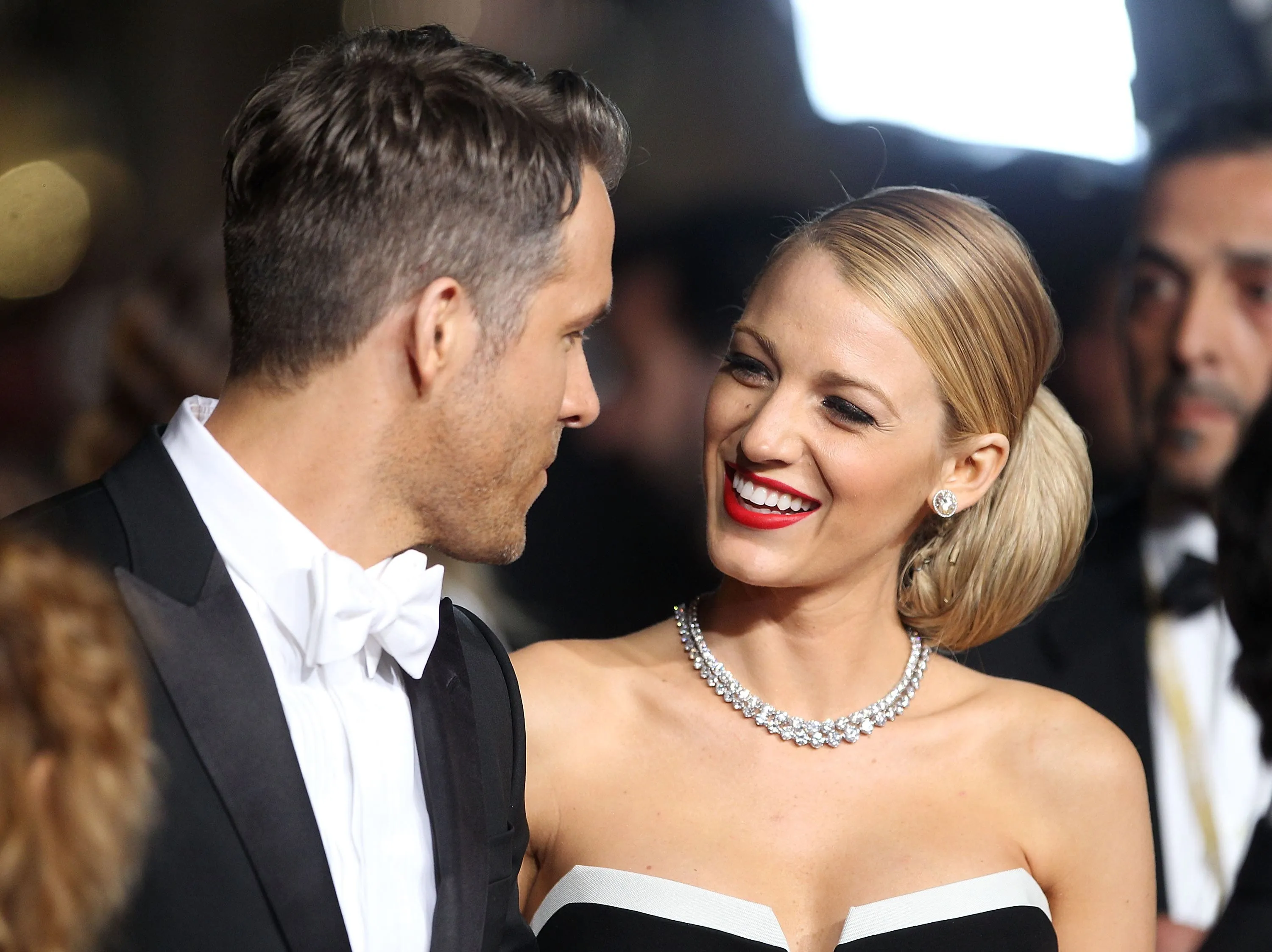 Wearing black tie outfits, Blake Lively and Ryan Reynolds smile at each other at the "Captives" Premiere