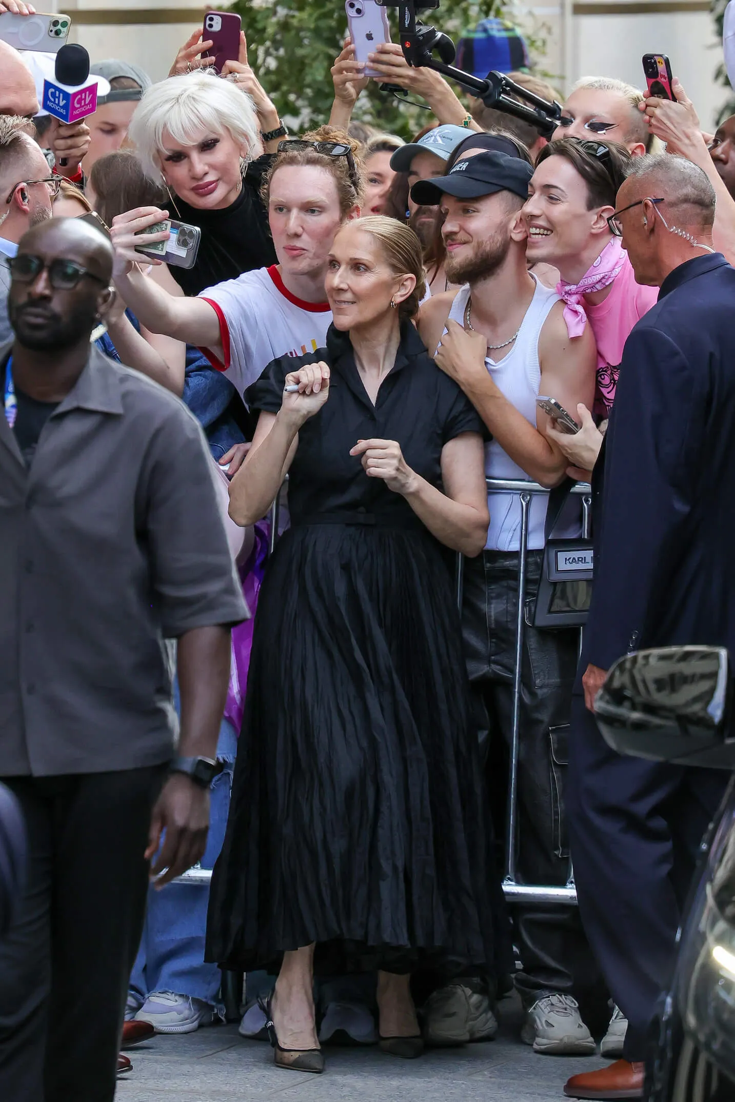 Céline Dion posing with fans while wearing a black Dior dress in Paris, France