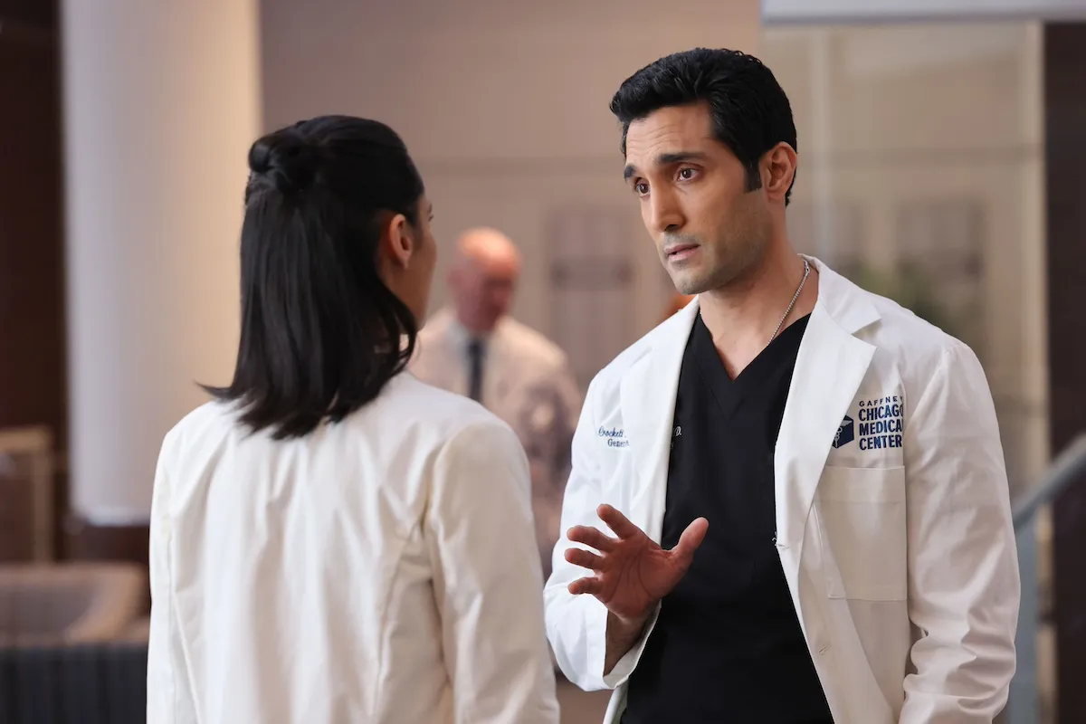 Dominic Rains wearing a white coat and talking to a woman in 'Chicago Med'