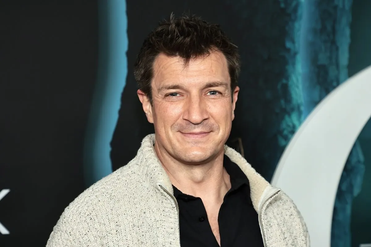 Nathan Fillion posing in a white sweater and black shirt at the premiere of 'Ozark' season 4.