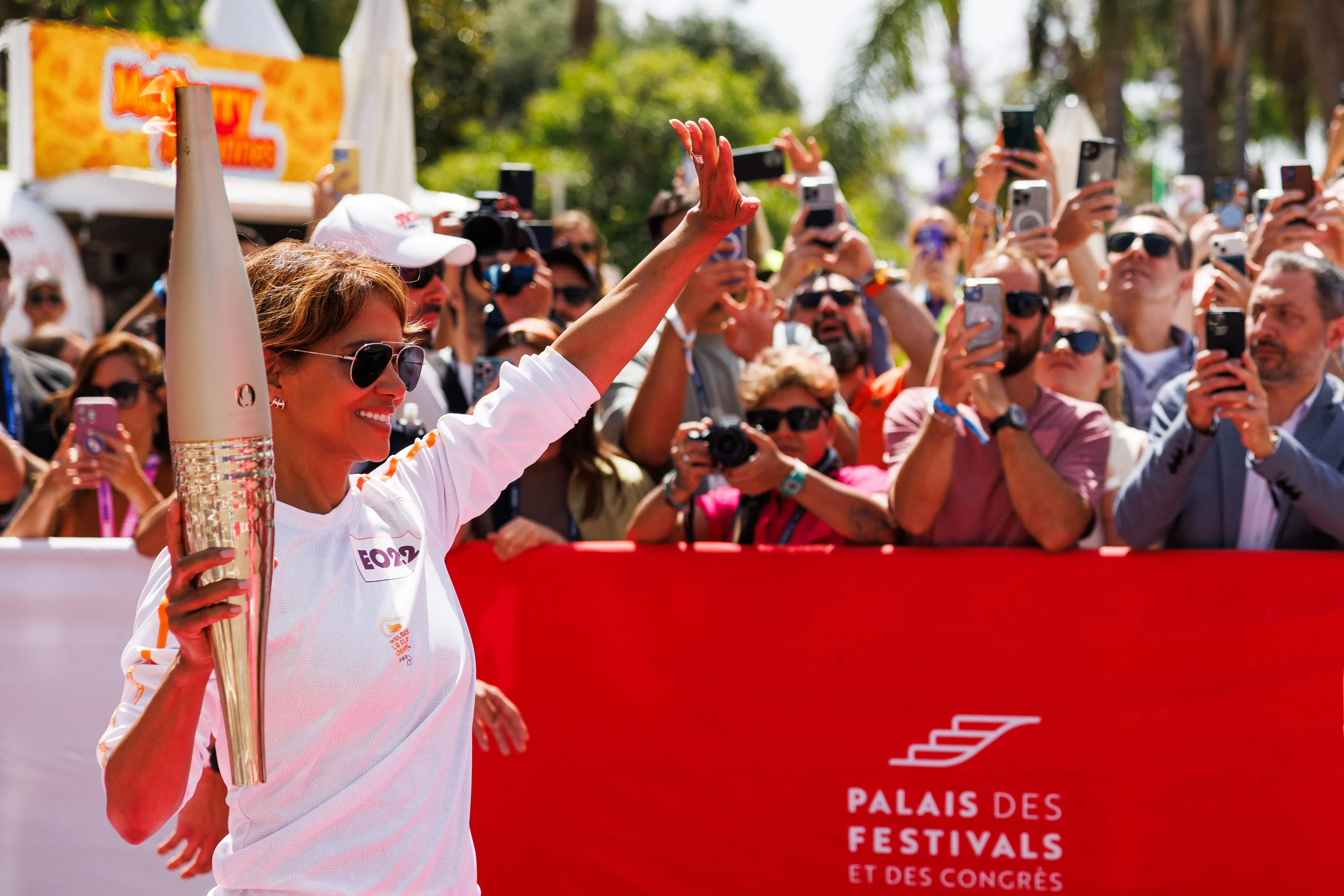 Actor Halle Berry holds the Olympic torch and waves at fans during opening ceremonies