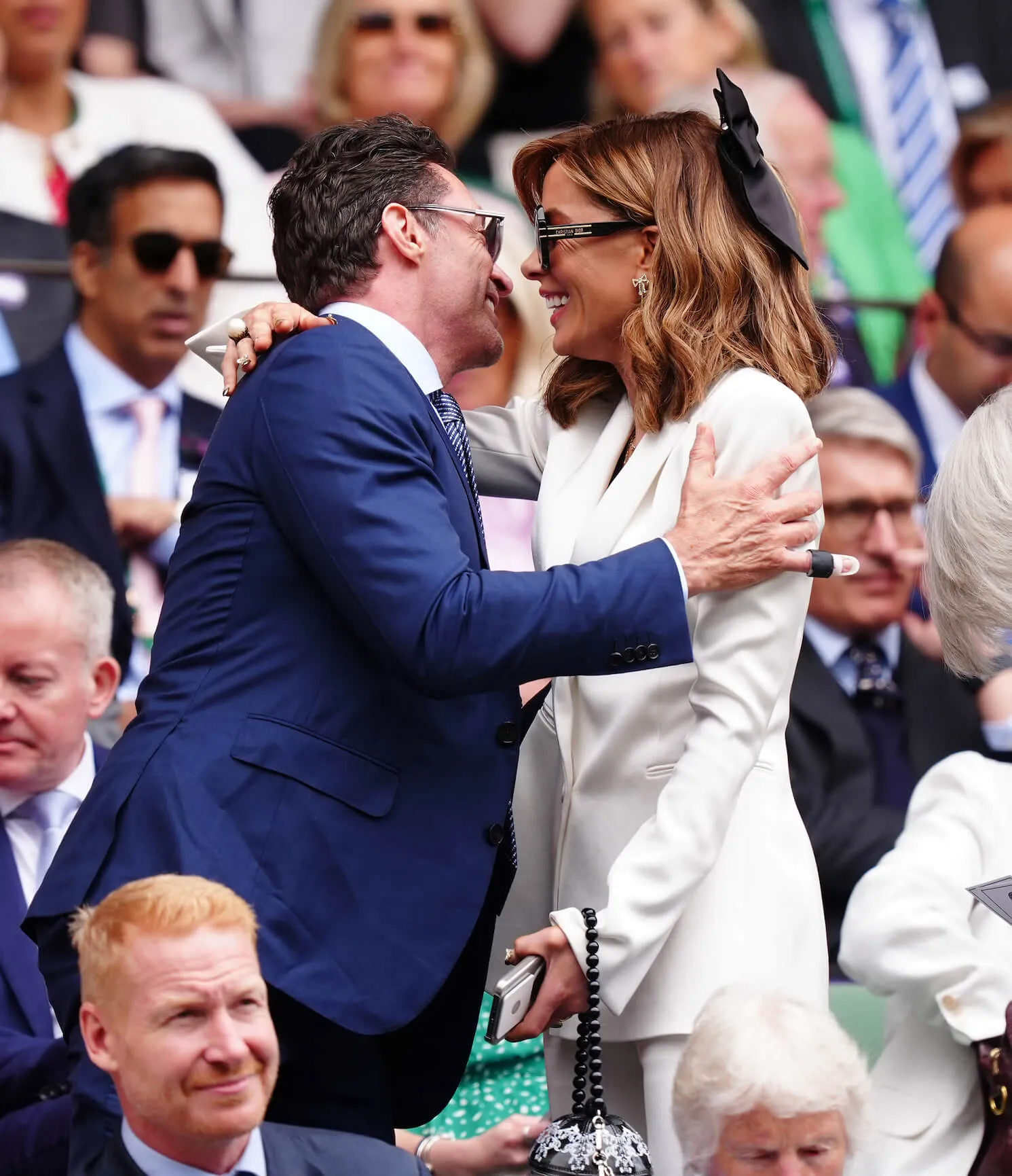 Hugh Jackman and Kate Beckinsale standing and getting ready to greet each other with a huge at Wimbledon in 2024