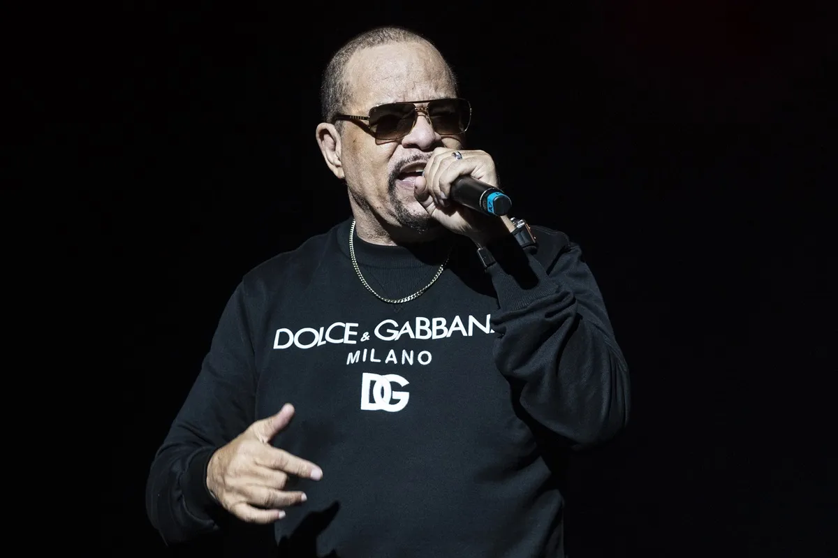 Ice-T performing on stage in a black shirt and sunglasses.