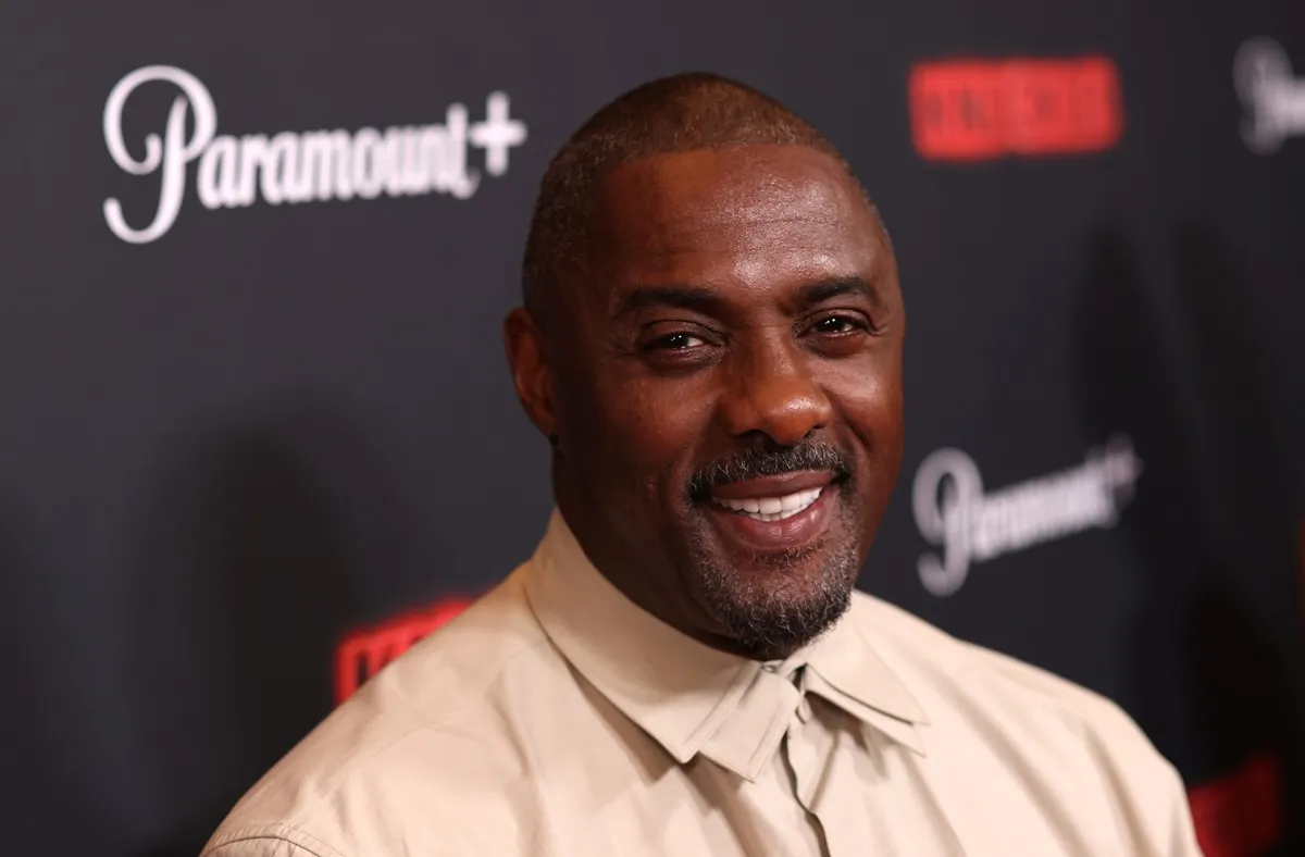 Idris Elba posing at the premiere of 'Knuckle' wearing a beige shirt.