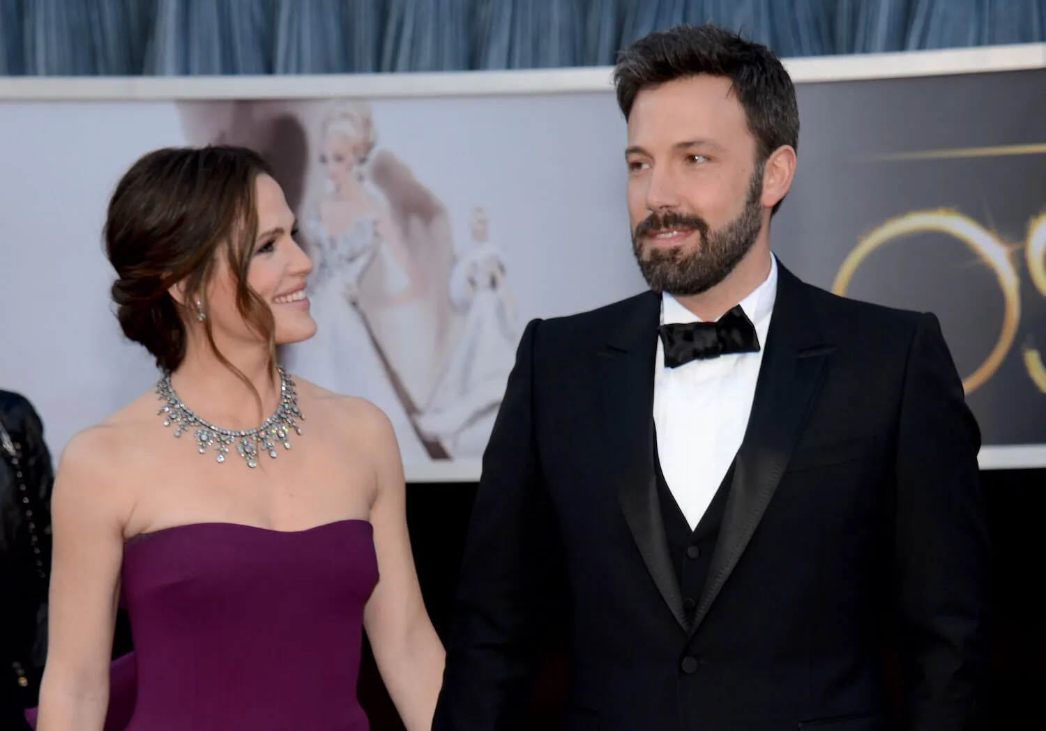 Jennifer Garner in a purple strapless dress looking next to her at Ben Affleck in a suit at the Academy Awards in 2013