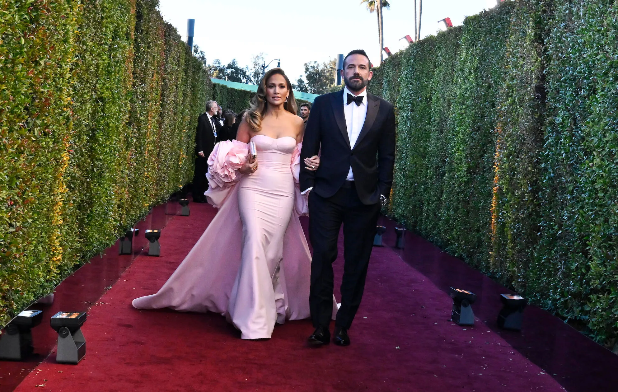 Jennifer Lopez in a pink gown and Ben Affleck in a tuxedo walking on the red carpet at the 81st Golden Globes in 2024