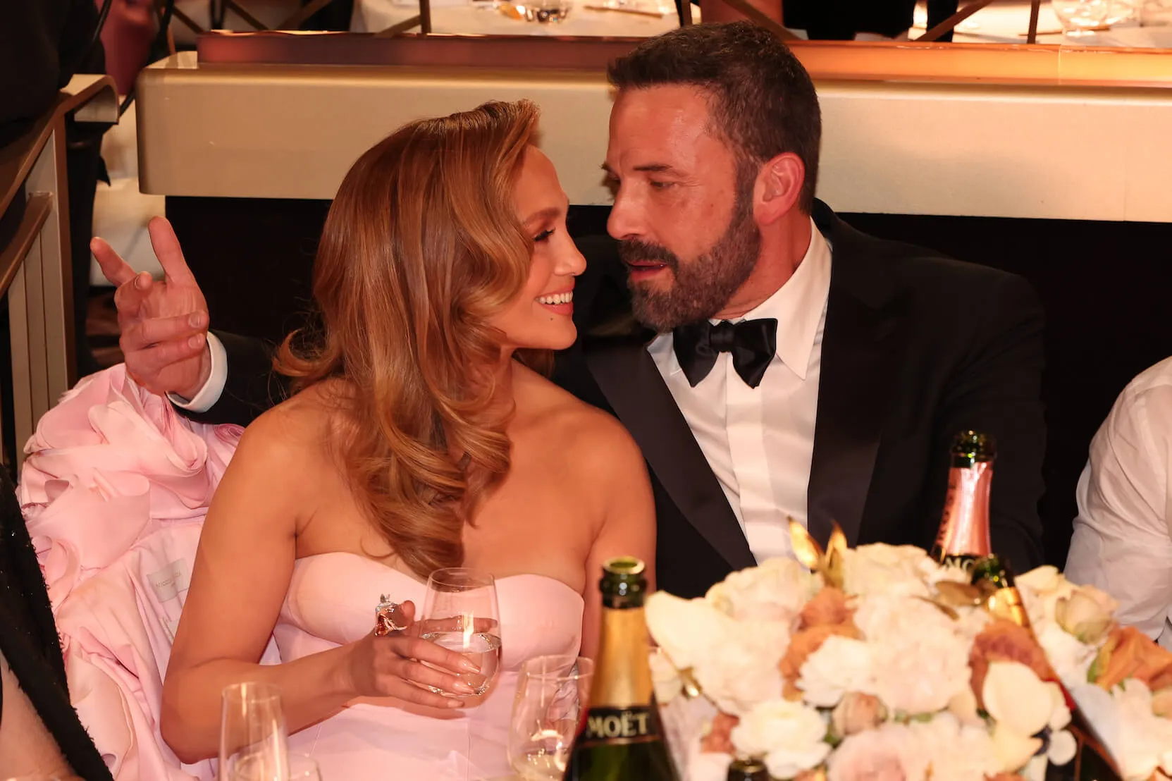 Jennifer Lopez and Ben Affleck sitting next to each other and looking at each other at the Golden Globes in 2024