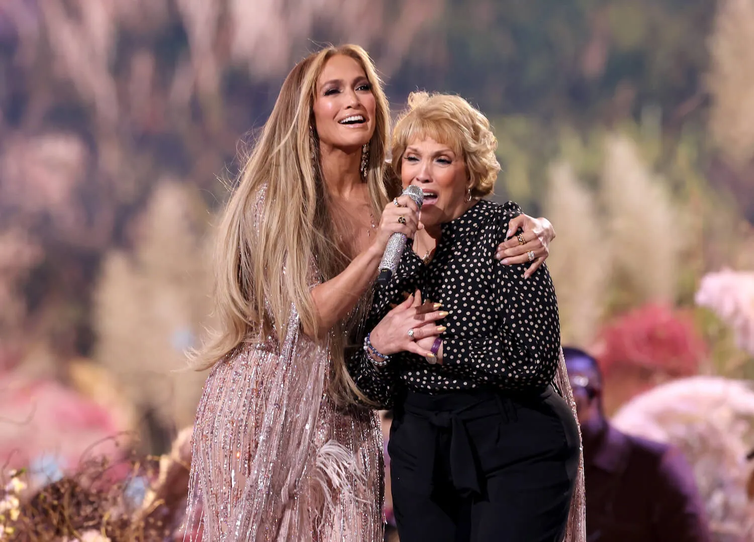 Jennifer Lopez holding a microphone for her mother, Guadalupe Rodríguez, while they perform onstage during Global Citizen VAX LIVE in 2021