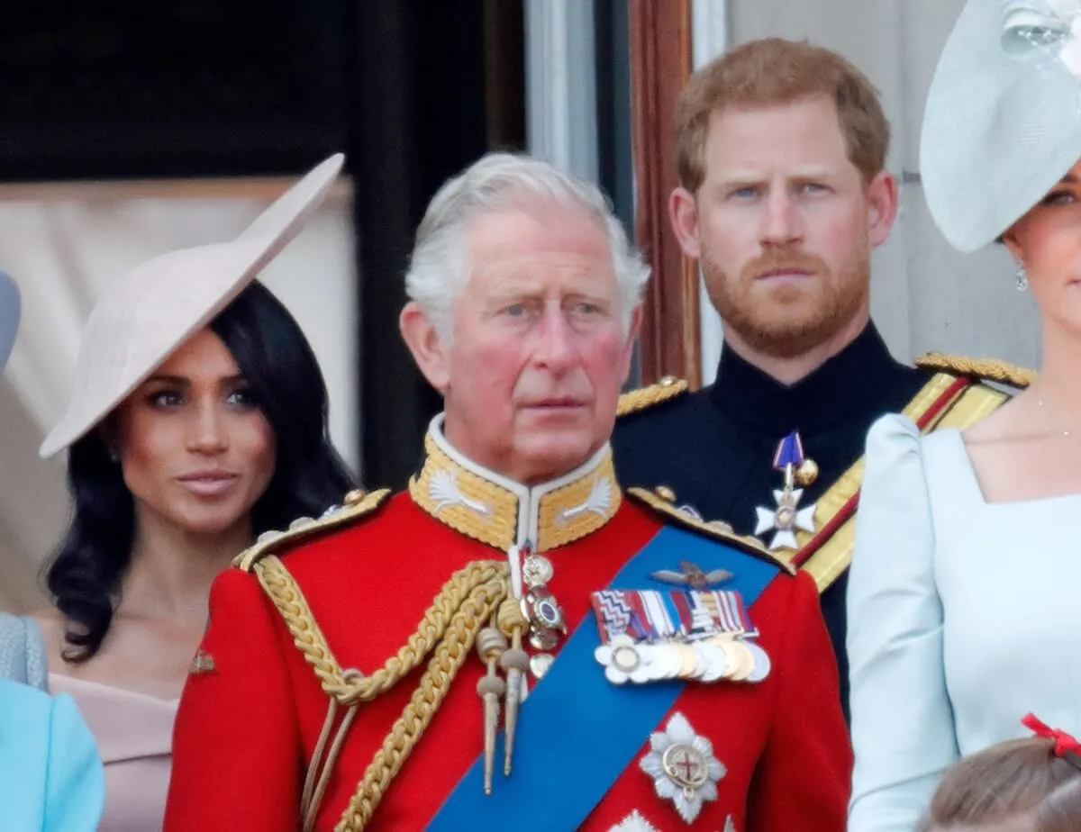 King Charles stands in front of Meghan Markle and Prince Harry