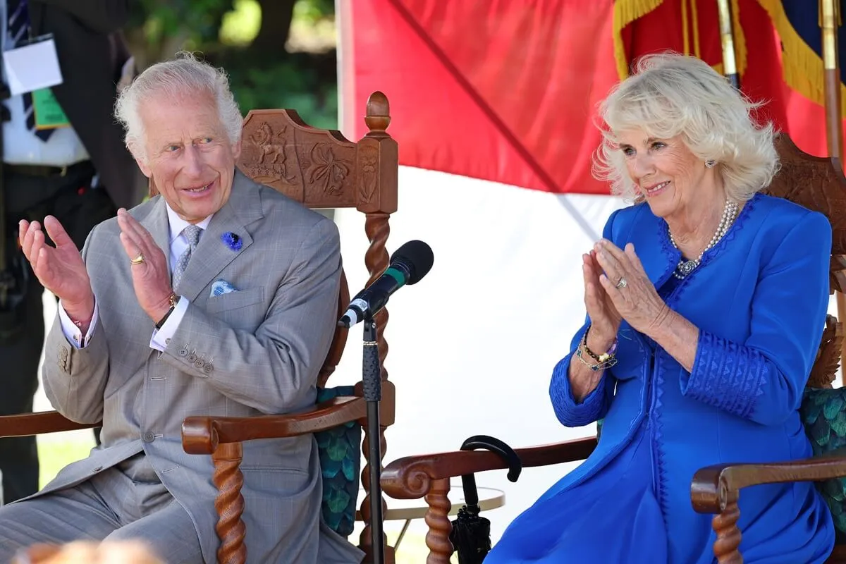 King Charles III and Queen Camilla clapping after children sing 'Happy Birthday' to the queen during a visit to Les Cotils in Guernsey