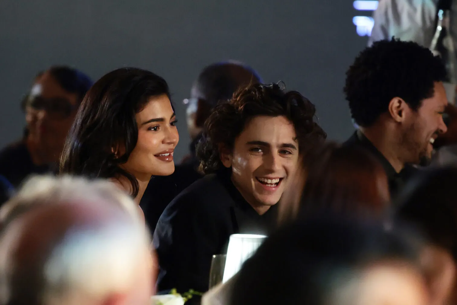 A distant photo of Kylie Jenner and Timothée Chalamet sitting next to each other and smiling at the WSJ Magazine Innovators Awards