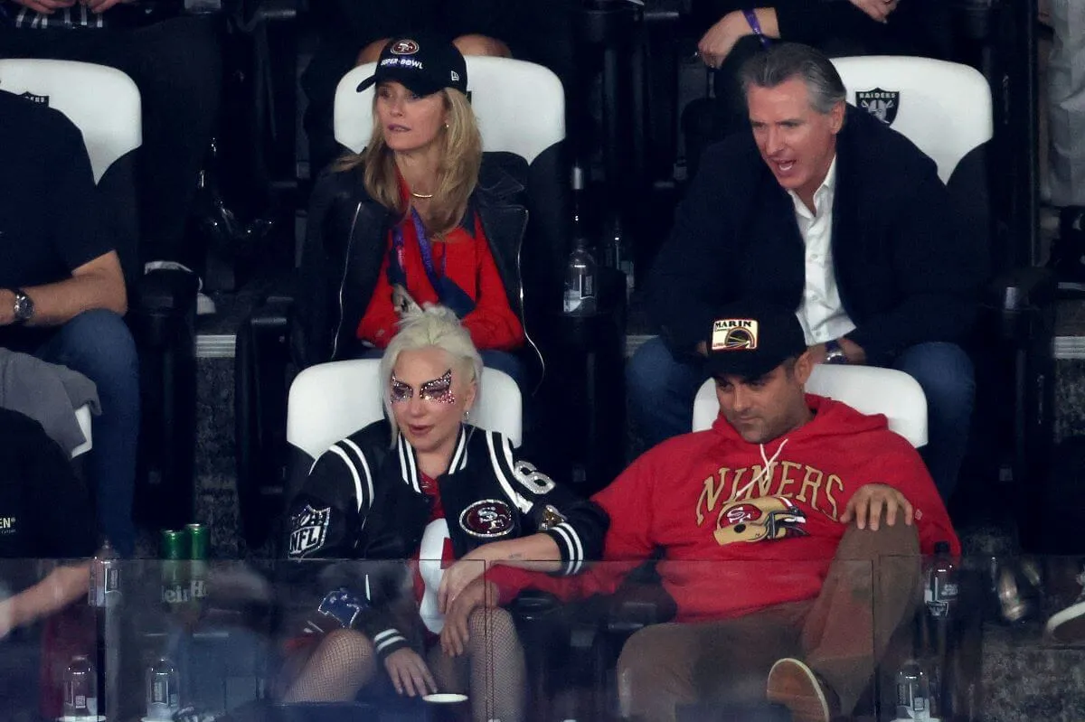 Lady Gaga and Michael Polansky hold hands and sit watching the Super Bowl.