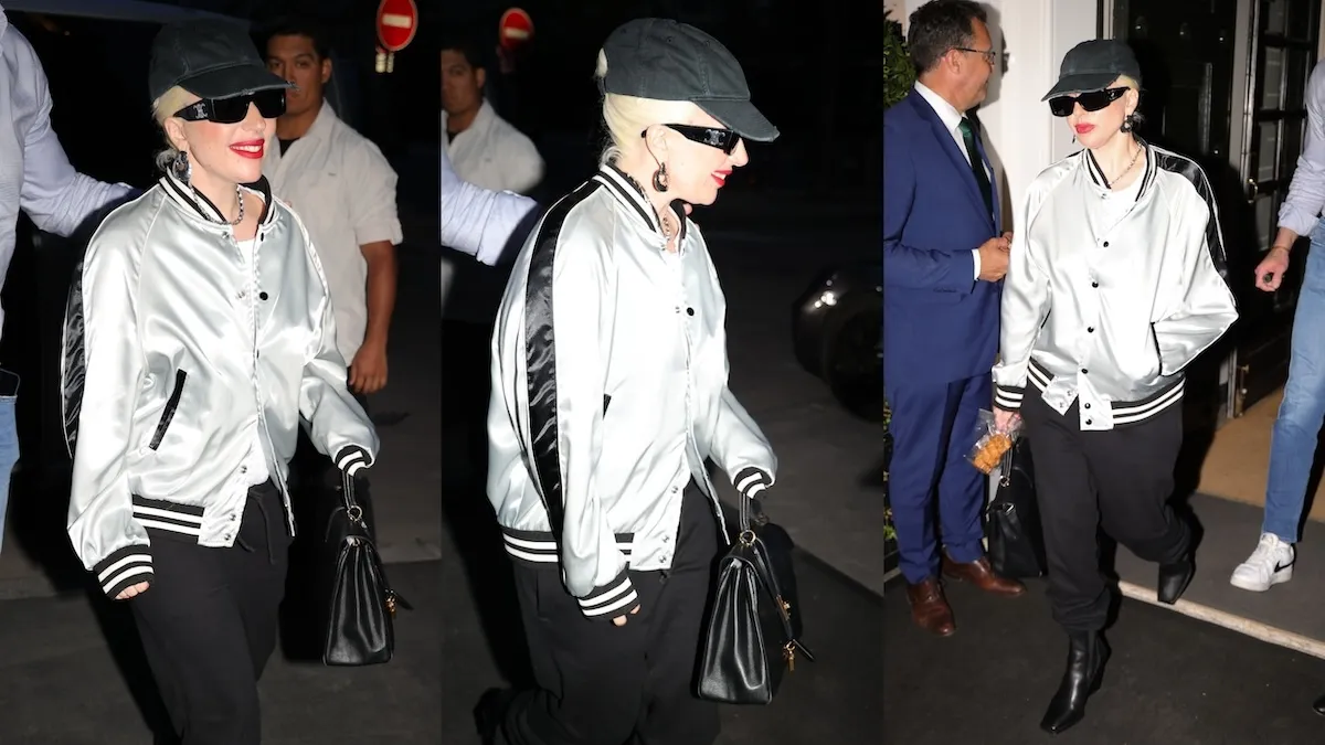 Wearing a black cap, Lady Gaga exits a Paris restaurant while cameras flash around here