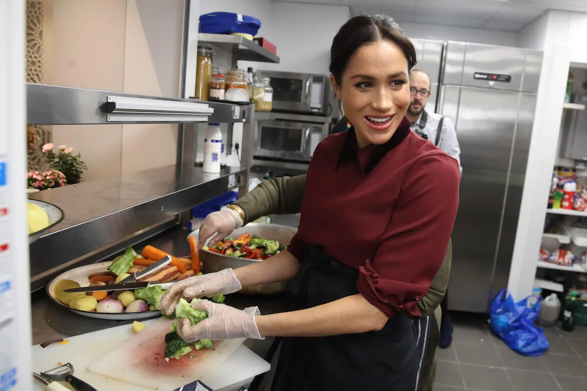 Meghan Markle, who 'enjoyed being back in front of the camera' filming her upcoming Netflix cooking and gardening show, in the kitchen cutting vegetables. 