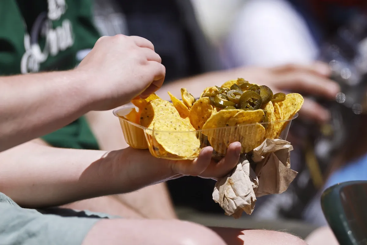 A person holding a tray of nachos with jalapenos