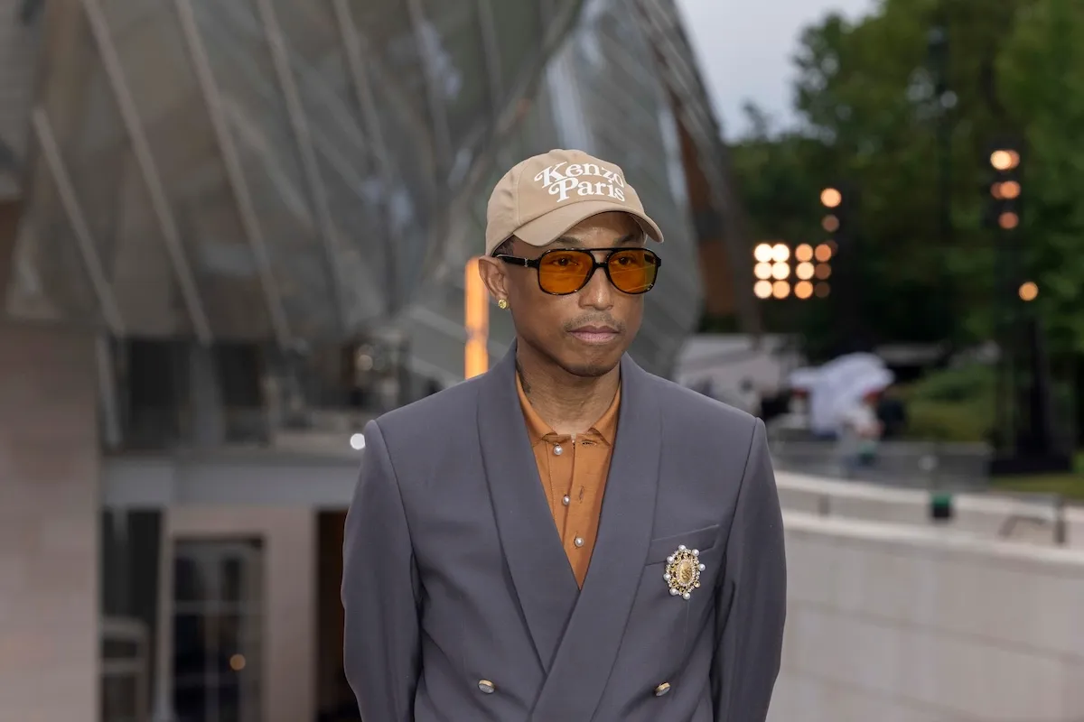 Rapper Pharrell Williams wears a navy blazer and carries a Louis Vuitton bag at The Prelude To The Olympics