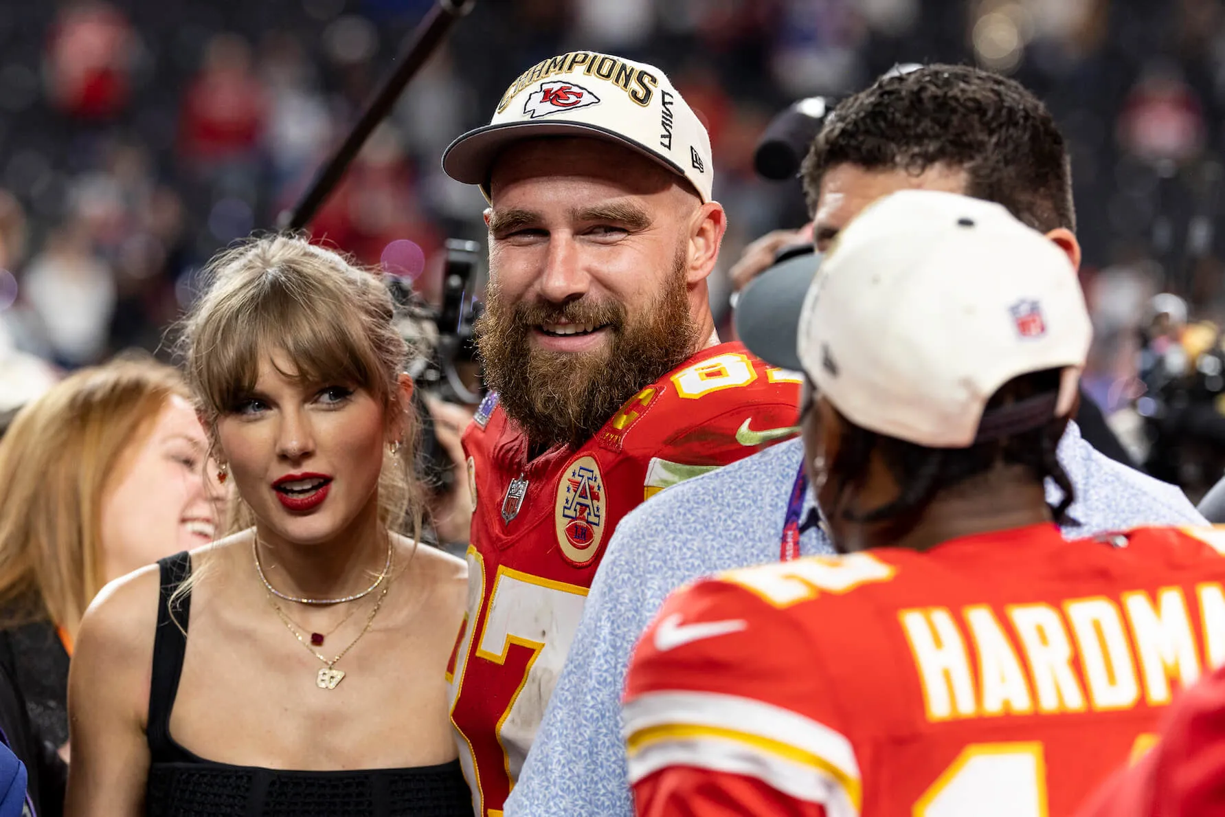 Travis Kelce and Taylor Swift stand next to each other and react as they see Mecole Hardman Jr., #12 of the Kansas City Chiefs, following the NFL Super Bowl 58 football game