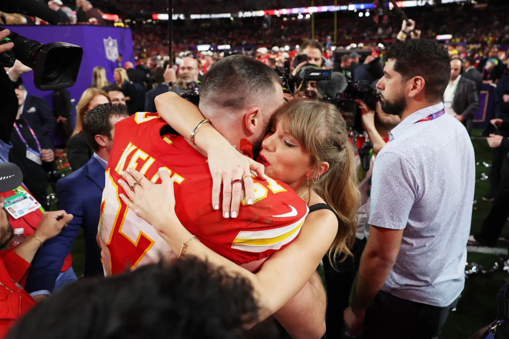 Travis Kelce and Taylor Swift embracing while surrounded by a crowd after the Super Bowl LVIII at Allegiant Stadium on Feb. 11, 2024