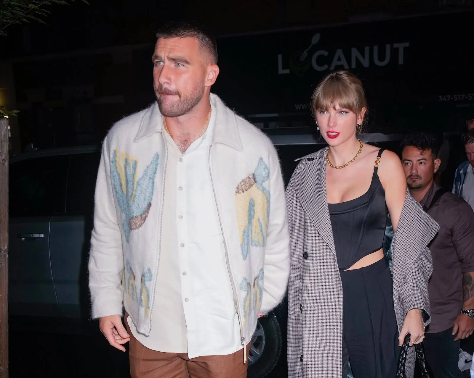 Travis Kelce and Taylor Swift walking hand in hand at night in October 2023