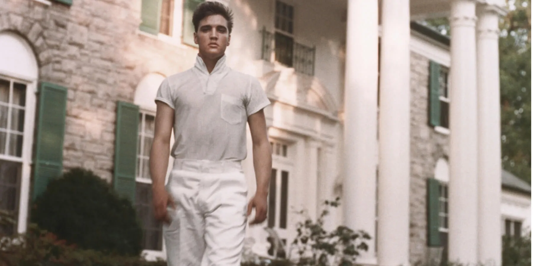 Elvis Presley posing in front of his Graceland home