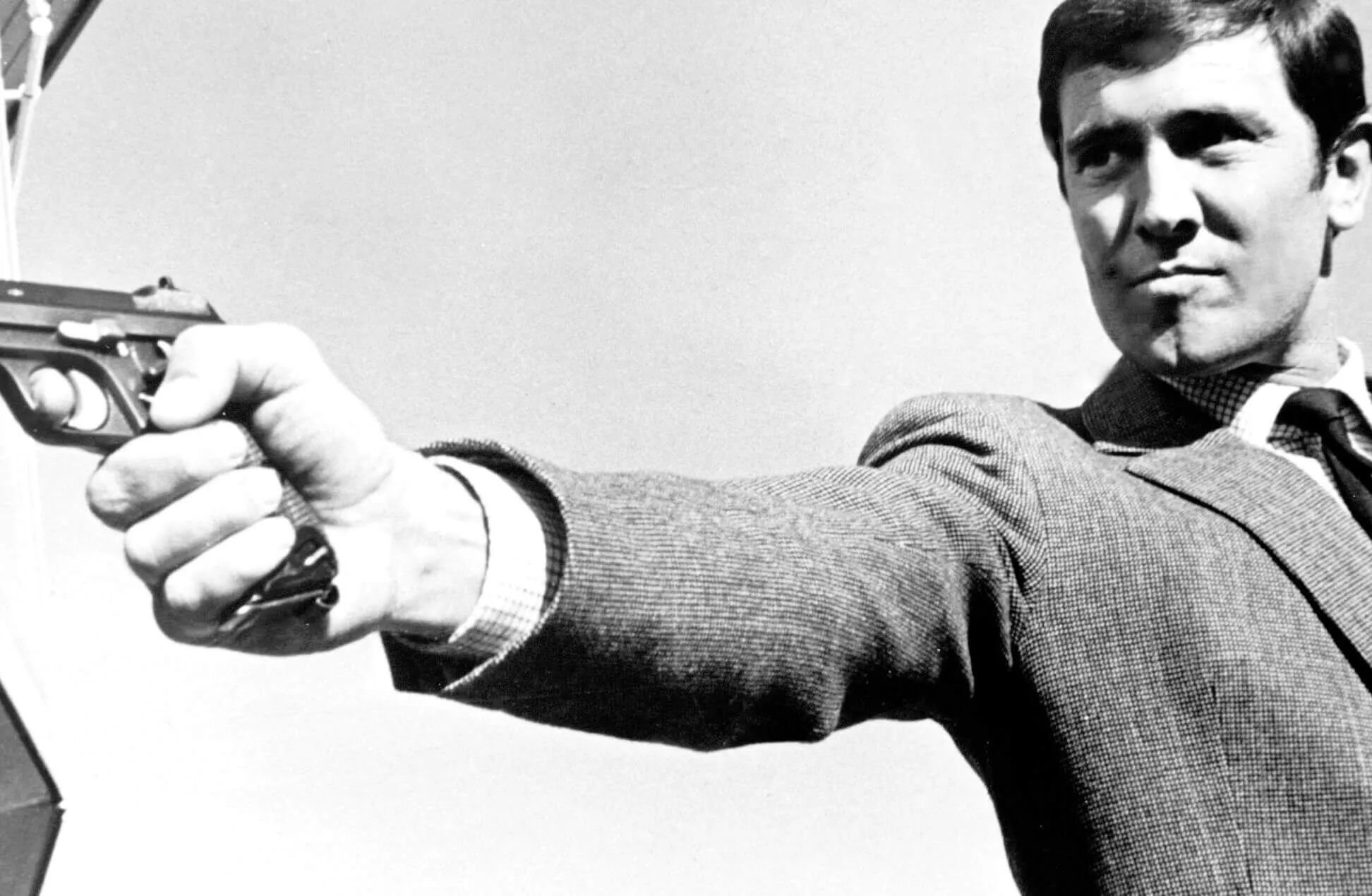 George Lazenby as James Bond holding a gun