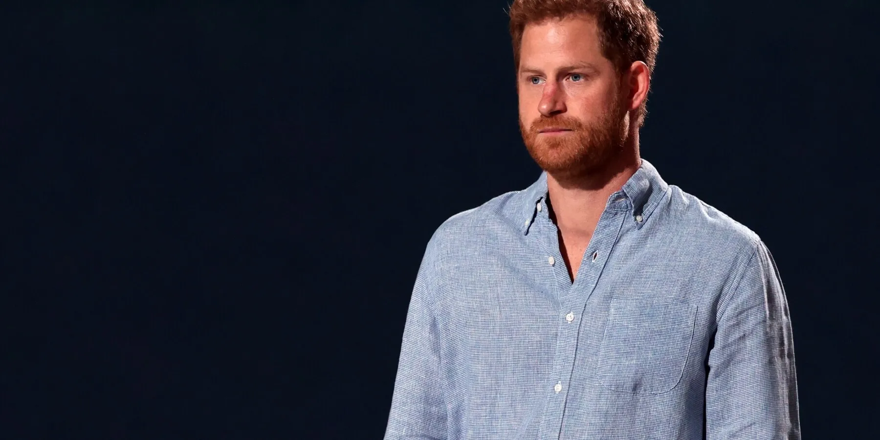 Prince Harry wearing a blue shirt on a black background