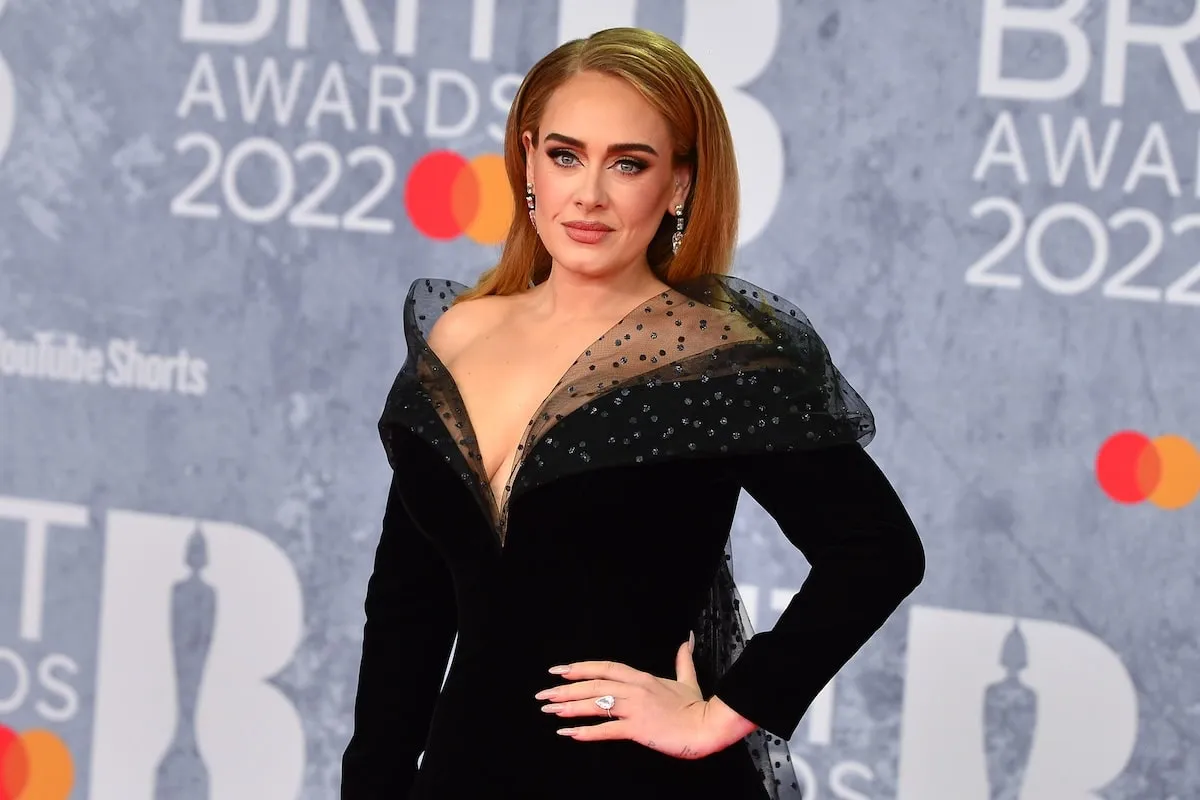 Wearing a black gown, Adele wears a pear-shaped ring on her left hand's ring finger at the 2022 Brit Awards