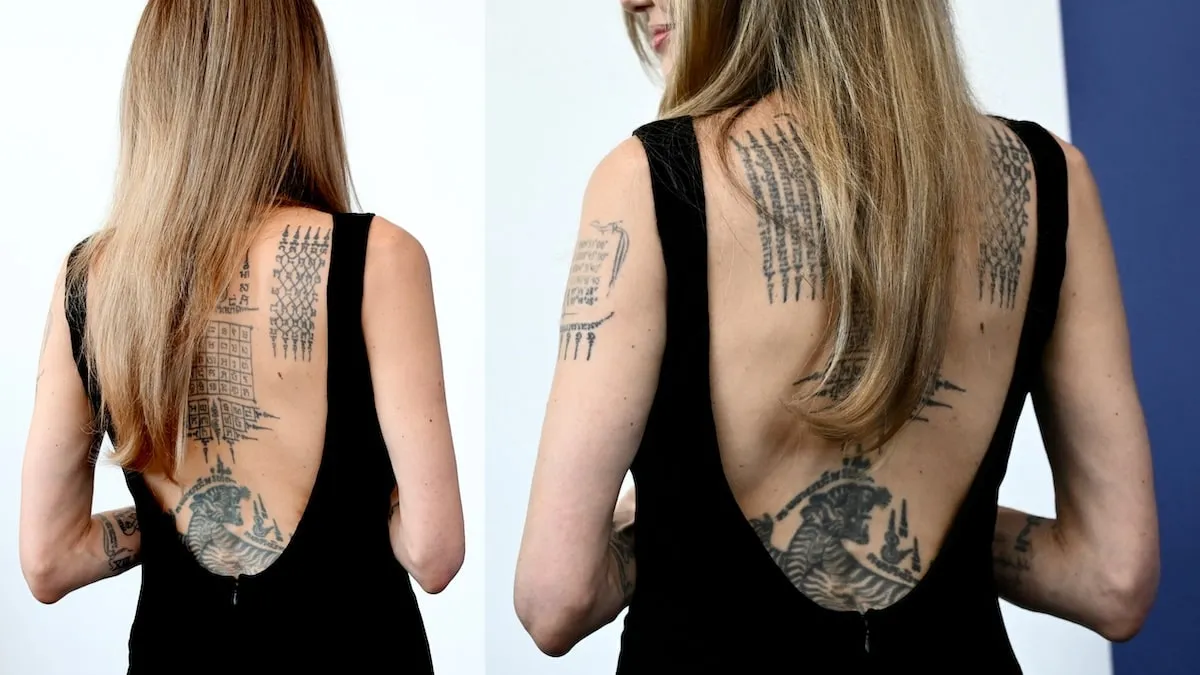 Wearing a black backless dress, Angelina Jolie turns away from cameras to show off her back tattoos