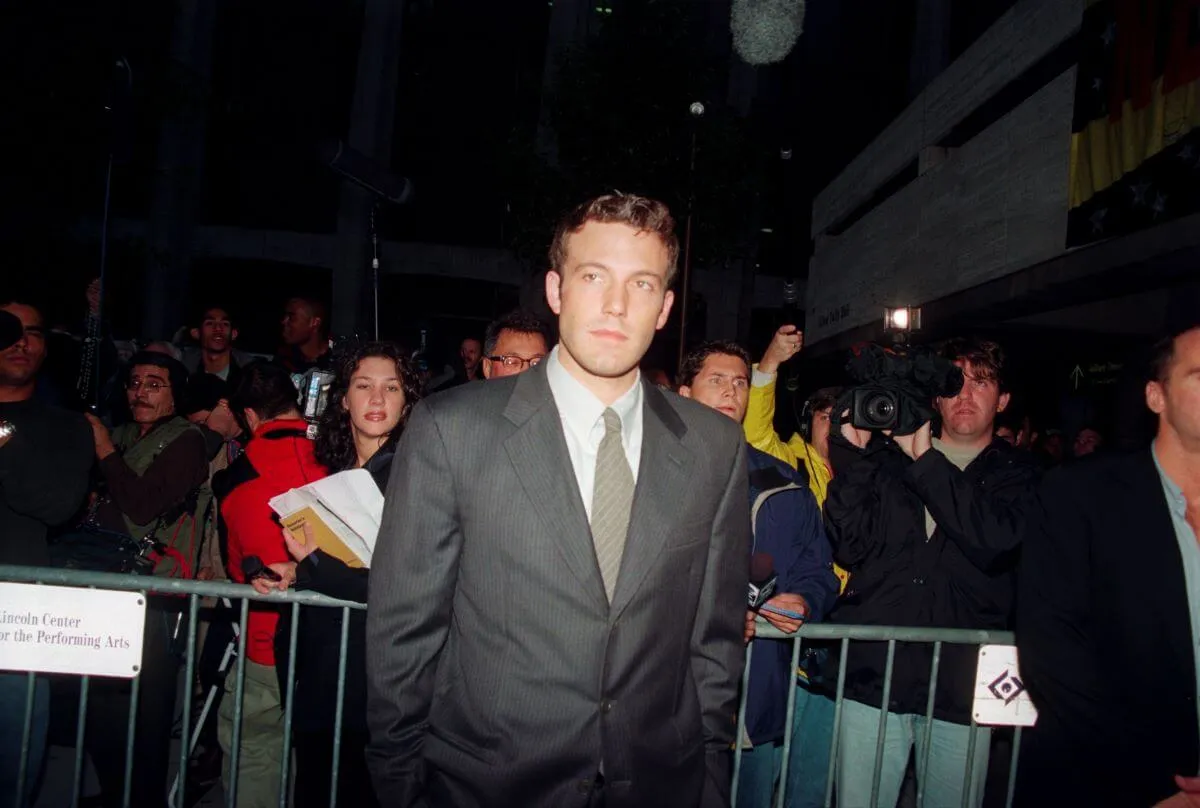 Ben Affleck wears a suit and stands in front of a crowd of people.