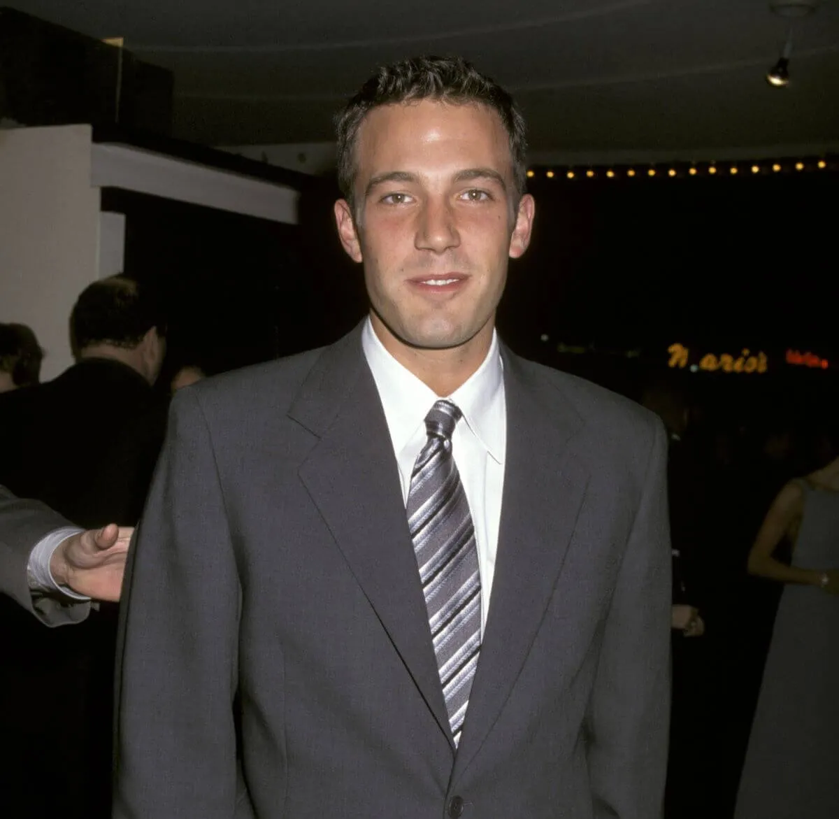 Ben Affleck wears a gray suit and stands.