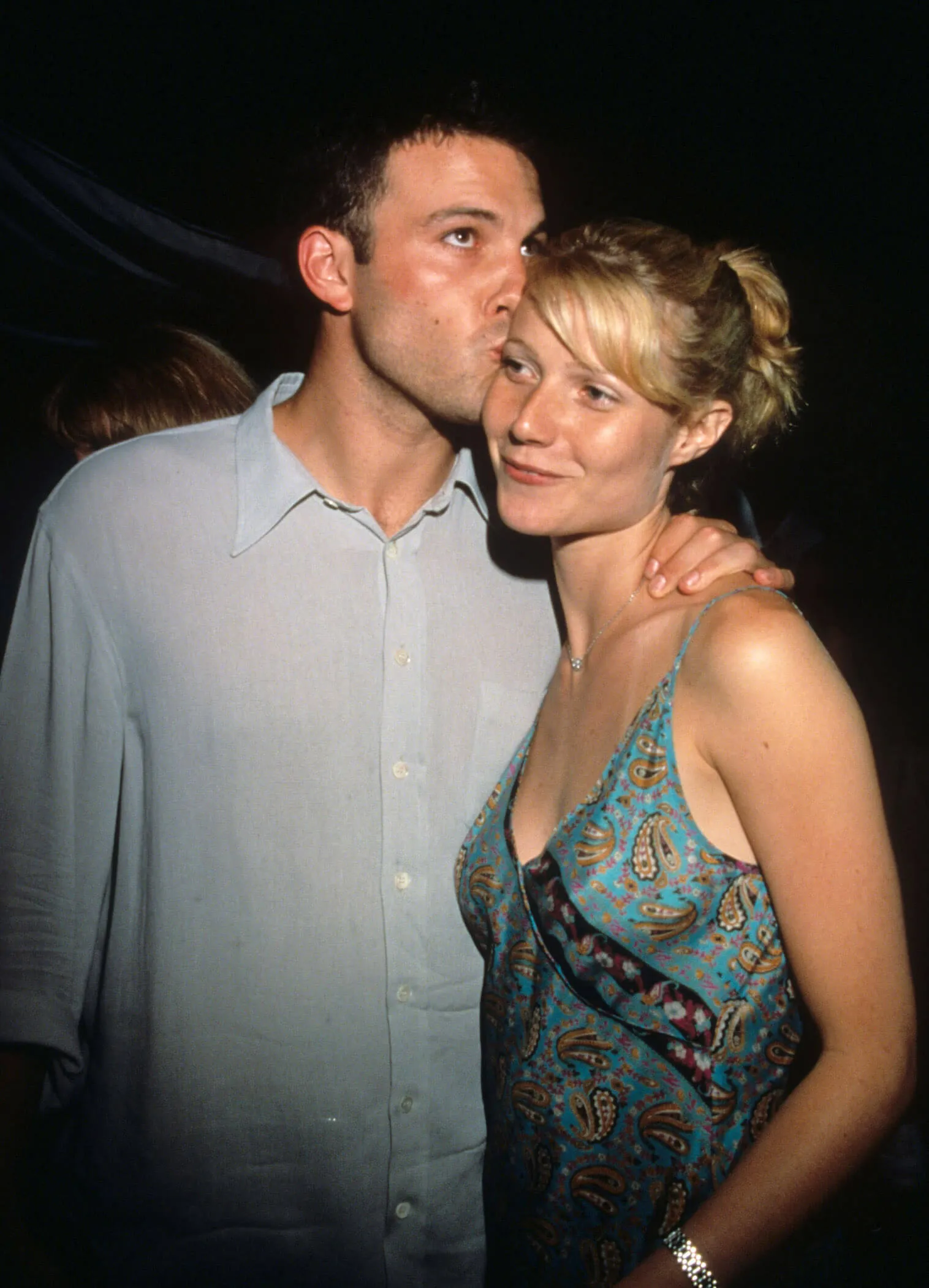 Ben Affleck kissing the side of Gwyneth Paltrow's head as she smiles with her mouth closed.