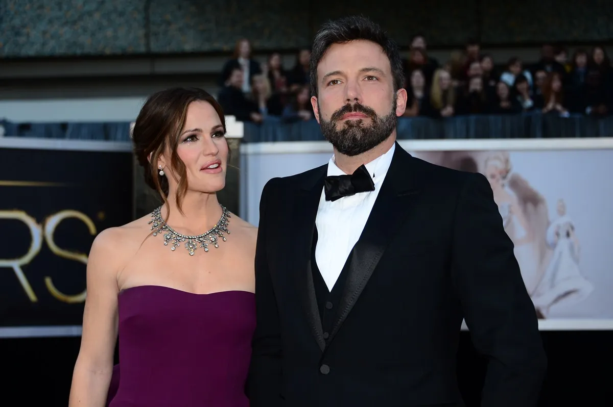 Ben Affleck in a suit posing at the Oscars next to Jennifer Garner who's wearing a dress.