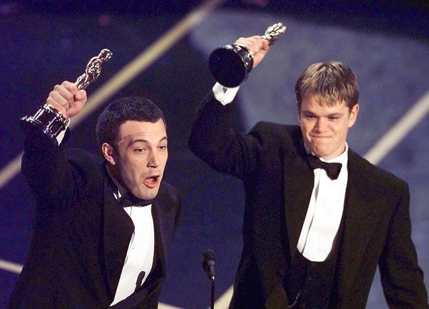 Ben Affleck (L) and Matt Damon looking shocked and happy as they hold up their Oscars after winning in the Original Screenplay Category during the 70th Academy Awards