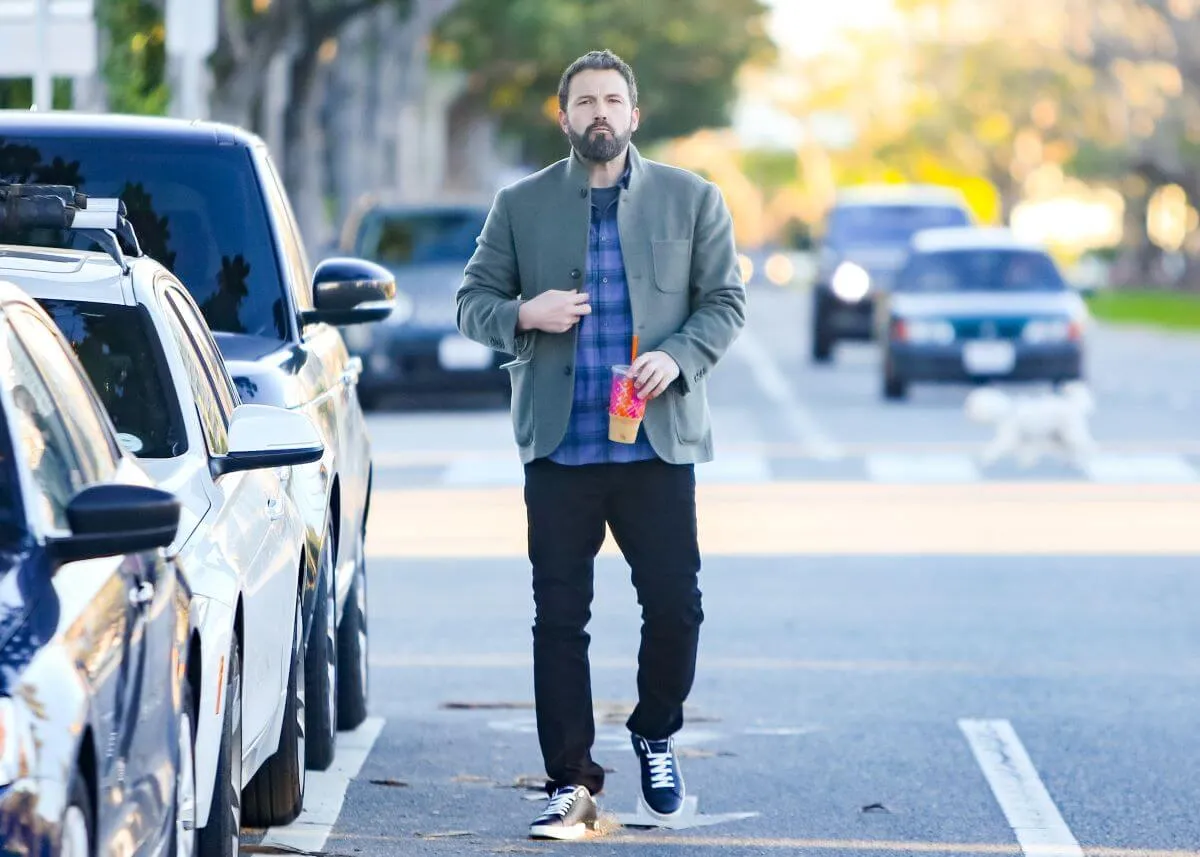 Ben Affleck walks on the street and holds an iced coffee.