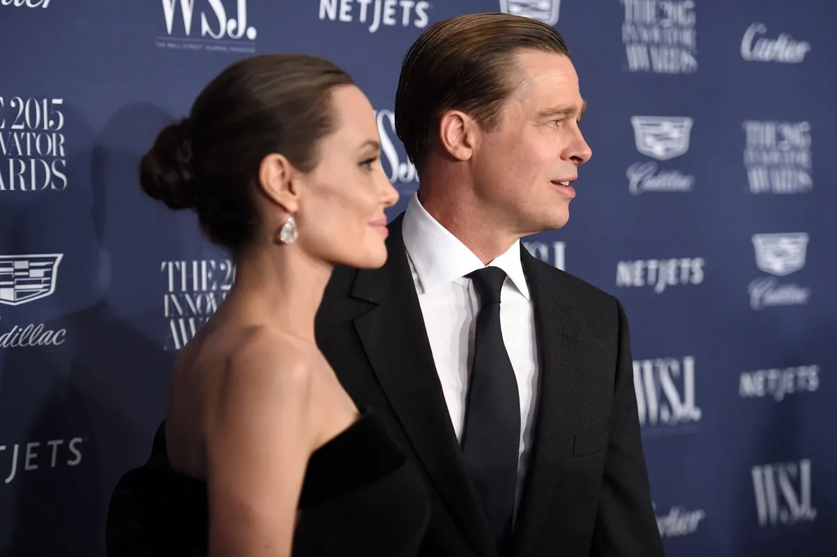 Brad Pitt and Angelina Jolie posing in a suit and dress respectively at the WSJ. Magazine 2015 Innovator Awards.