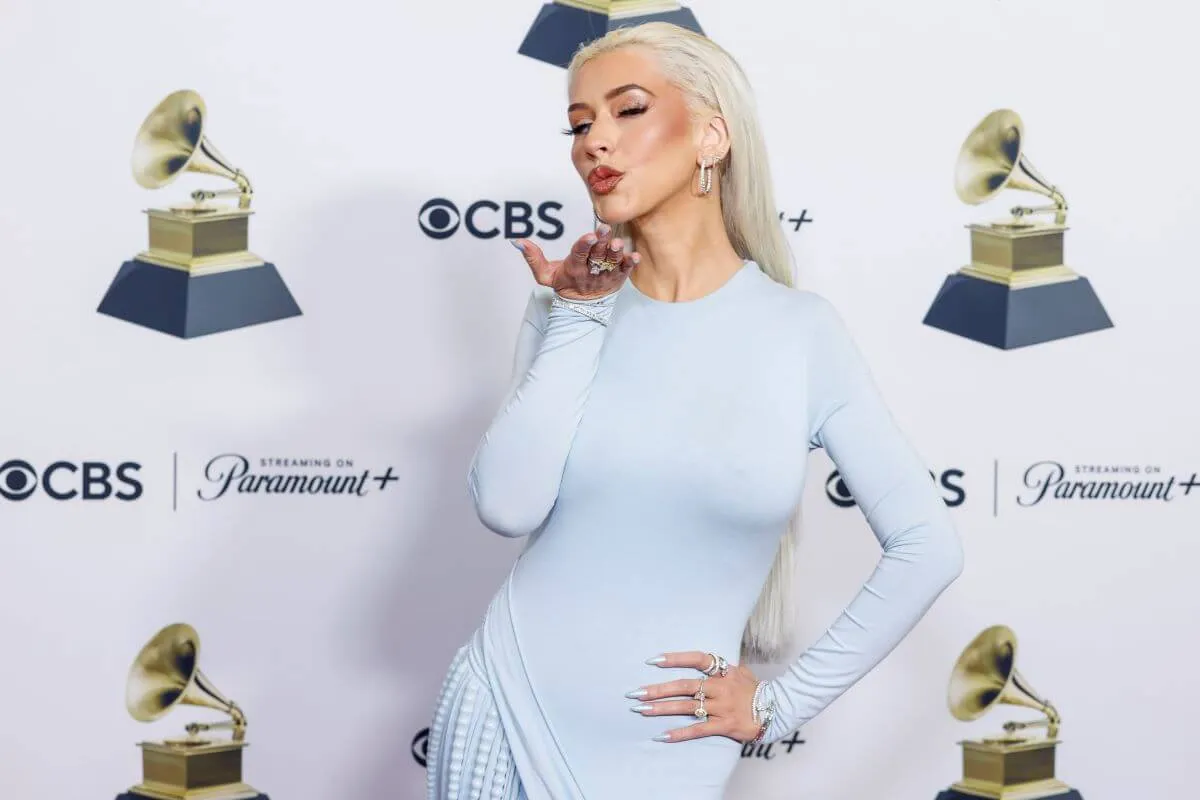 Christina Aguilera wears a white dress and blows a kiss at the Grammys.