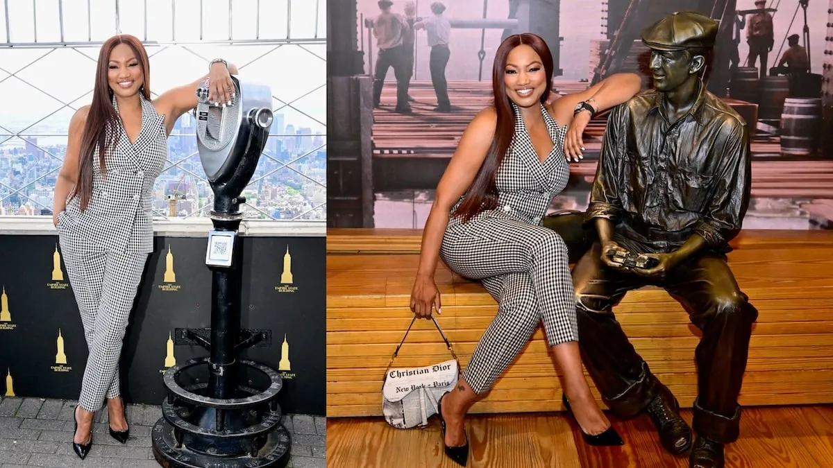 Wearing a checkered pant suit, Garcelle Beauvais stands at the top of the Empire State Building