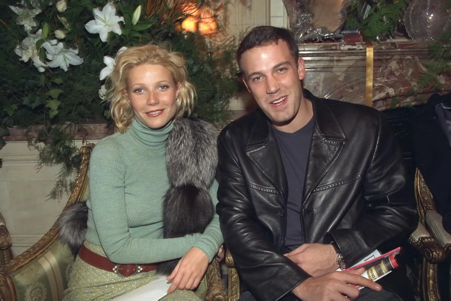 Gwyneth Paltrow and Ben Affleck sitting next to each other and smiling in 1999