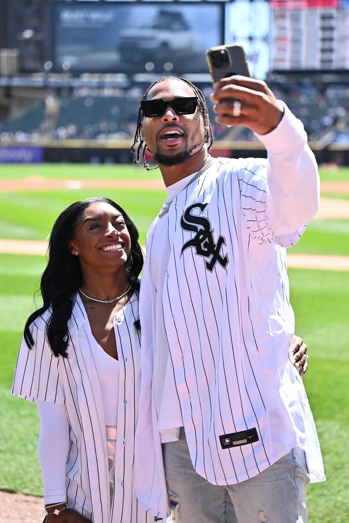 Gymnast Simone Biles and Jonathan Owens of the Chicago Bears record a video on the field before Owens threw out a first pitch before a game between the Cincinnati Reds and the Chicago White Sox