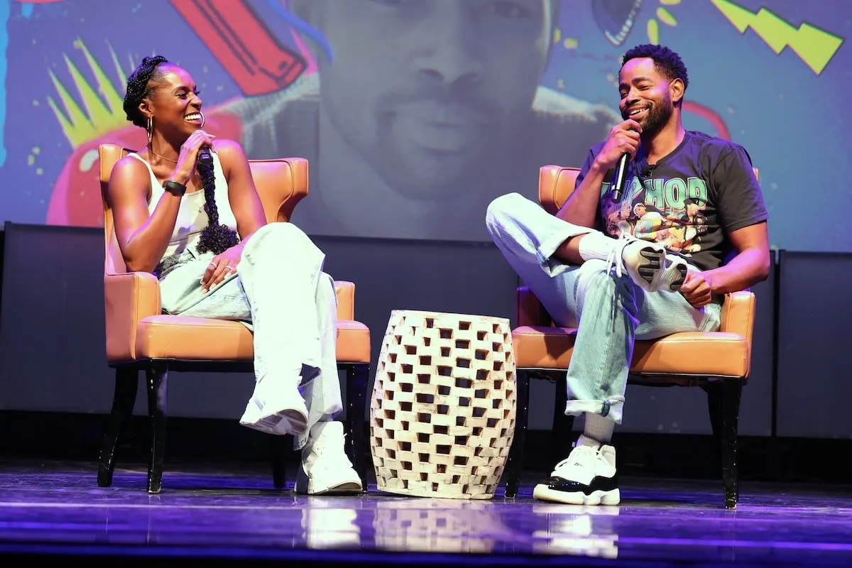 Actors Issa Rae and Jay Ellis laugh together on stage at his book release event