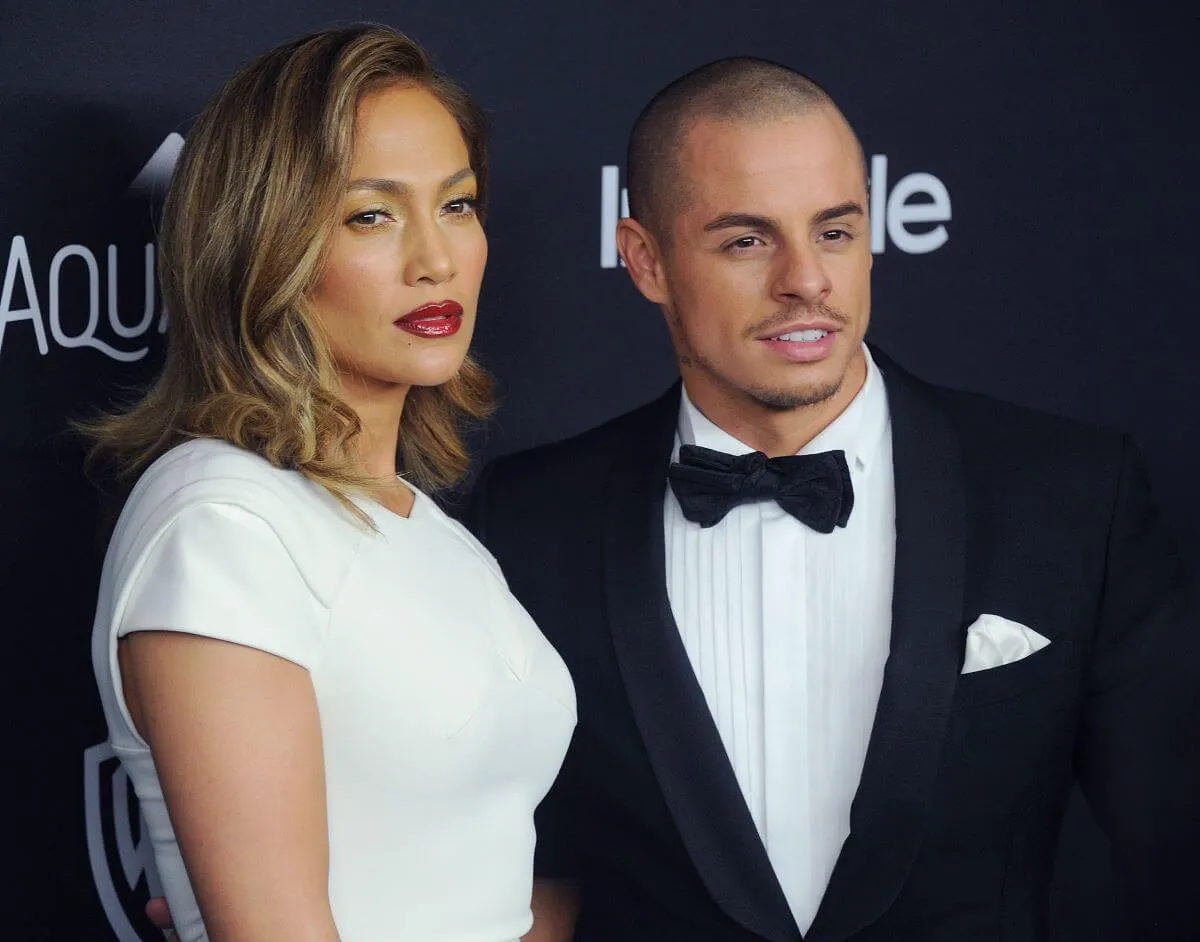 Jennifer Lopez wears a white dress and stands with Casper Smart, who wears a tuxedo.