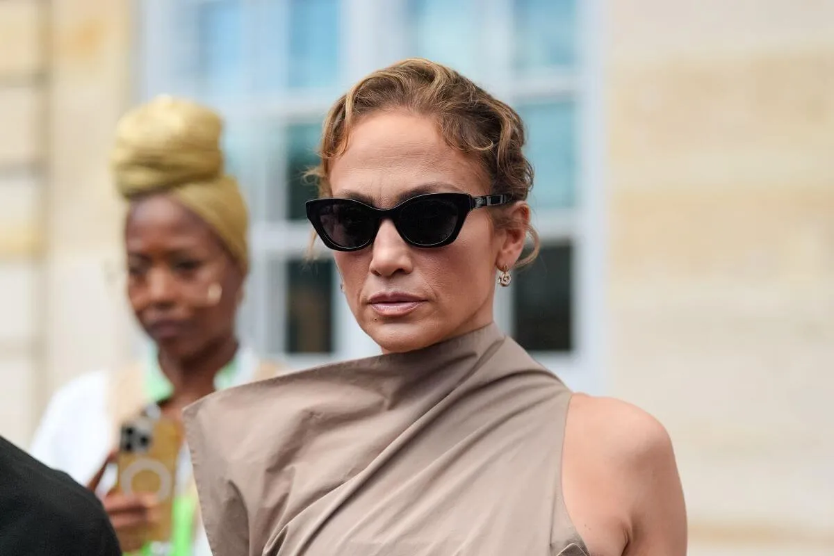 Jennifer Lopez wears a tan dress and sunglasses.