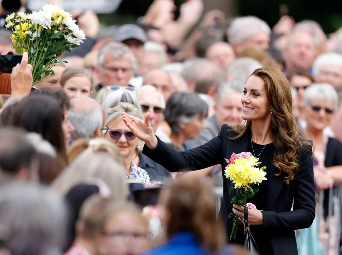 Kate Middleton receives bouquets of flowers as she meets members of the public after viewing floral tributes left at the entrance to Sandringham House to Queen Elizabeth II