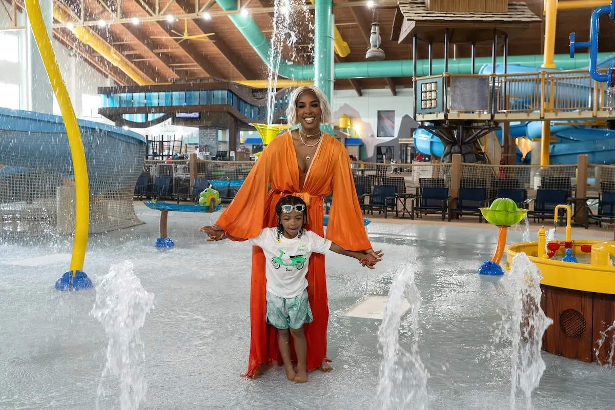 Wearing an orange kaftan, Kelly Rowland plays with her son Noah at Great Wolf Lodge water park