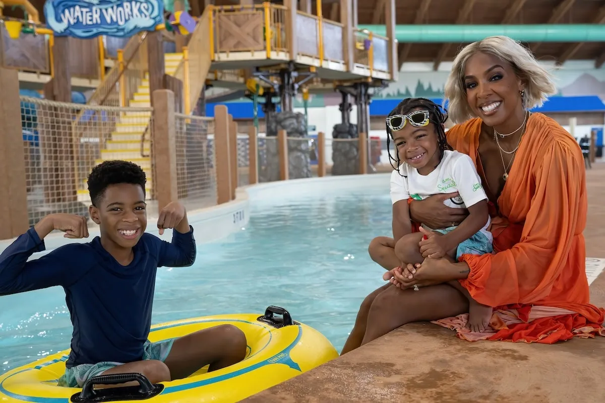 Wearing an orange kaftan, Kelly Rowland plays with her sons Titan and Noah at Great Wolf Lodge water park