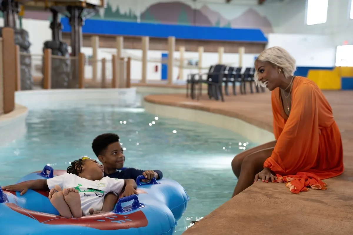 Wearing an orange kaftan, Kelly Rowland plays with her sons Titan and Noah at Great Wolf Lodge water park